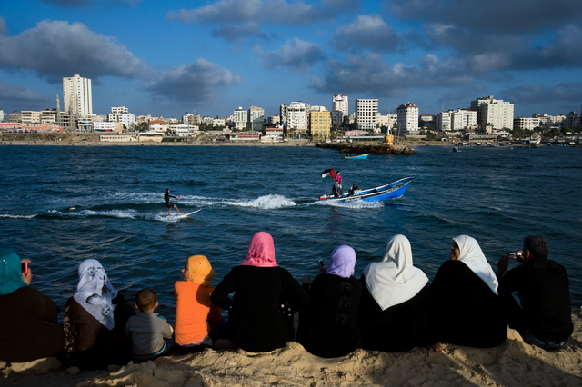 Gaza, women look at Mahmoud Osama Al-Rayashi waterskiing in the port of Gaza City.