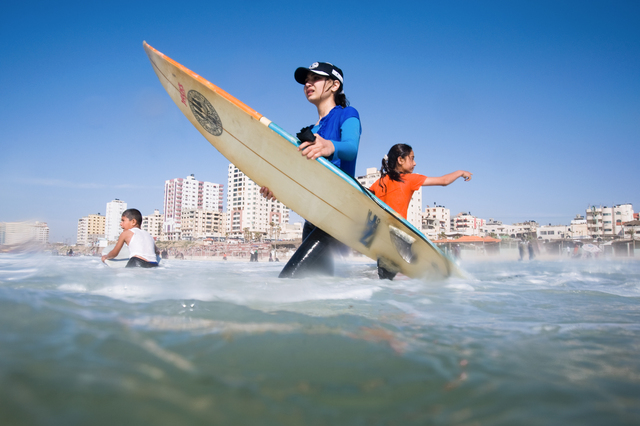 Gaza City, young surfer girls into the water in front of the Annadi Al Bahri Marine Club. Center, Shorouq Abu Ghanem (14) and right her sister Sabah Abu Ghanem (12).