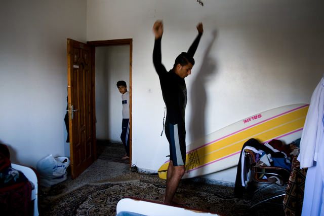 Gaza, Mahmoud Osama Al-Rayashi in his room as he puts on a wetsuit, observed by his little brother.