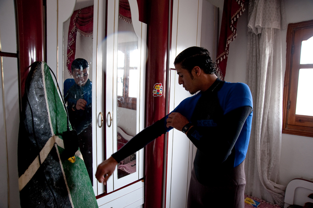 Gaza, Mahmoud Osama Al-Rayashi in his room as he puts on a wetsuit