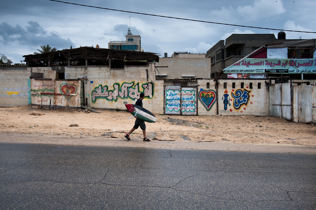 Gaza, a surfer walking along the seafront