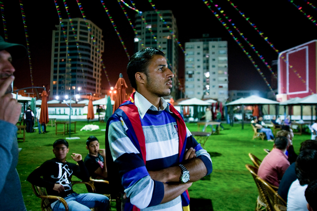 Gaza, surfer Mahmoud Osama Al-Rayashi (center) watches at football match Barcelona-Real Madrid with friends in a open air restaurant.