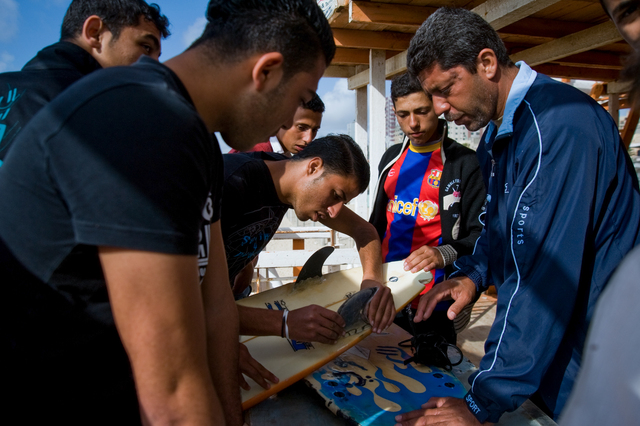 Gaza, surfer Mahmoud Osama Al-Rayashi (center) is reparing his surf board at the Annadi Al Bahri Marine Club together with Yosef Abu Ghanem (Barcelona t-shirt), Al Hindi Ashour (right) and friends.
