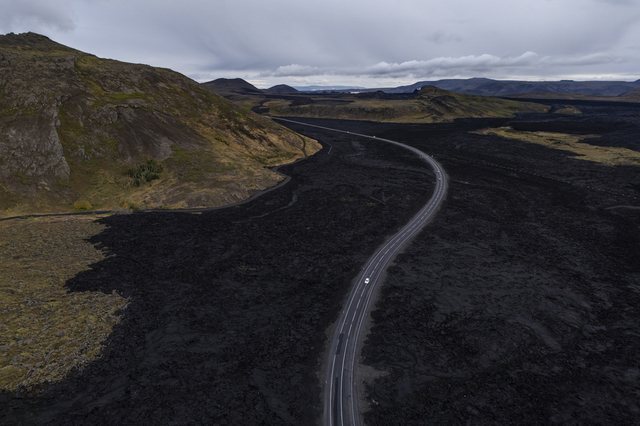 Grindavik (Iceland): a few cars are driving along the road linking the village to the Blue Lagoon area. The road on the left, which is closed, has been covered by lava that flowed as a result of volcanic activity, which led to nine eruptions between December 2023 and August 2025: Iceland’s landscape is changing extremely rapidly, even from a geological perspective.